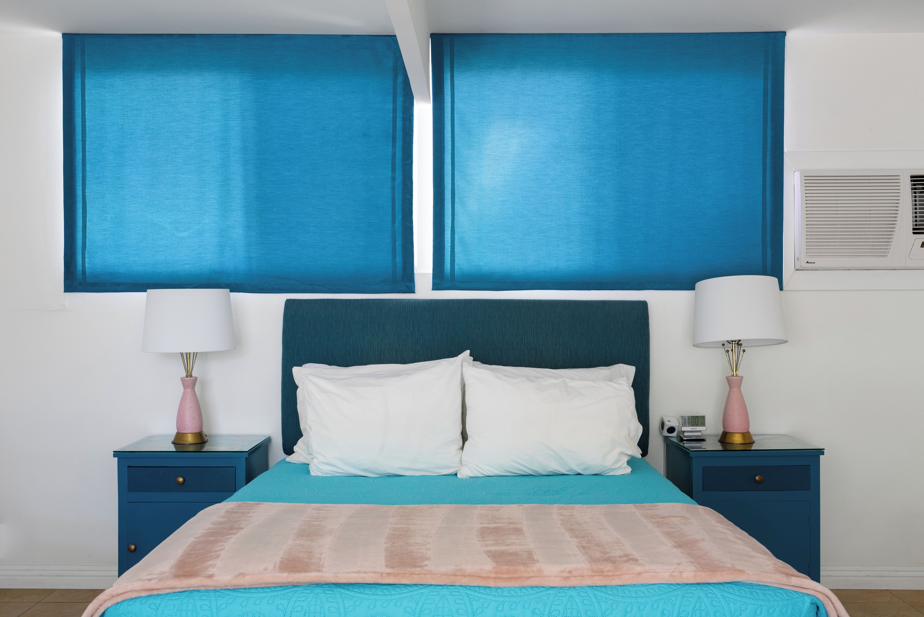 A bedroom with a large bed, two nightstands, and a wall-mounted air conditioner.
