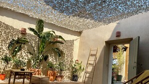 A wooden deck with potted plants, a wooden chair, and a ladder against a wall. - Outbuilding of a 4-star house, swimming pool, patio, private parking, air conditioning, sleeps 2/3 (La Ciotat)