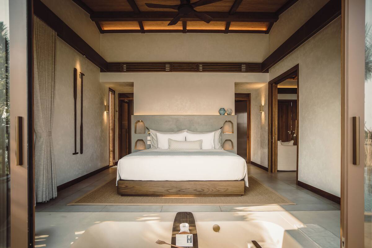 Un dormitorio espacioso con una cama grande, ventilador de techo y vistas al exterior.