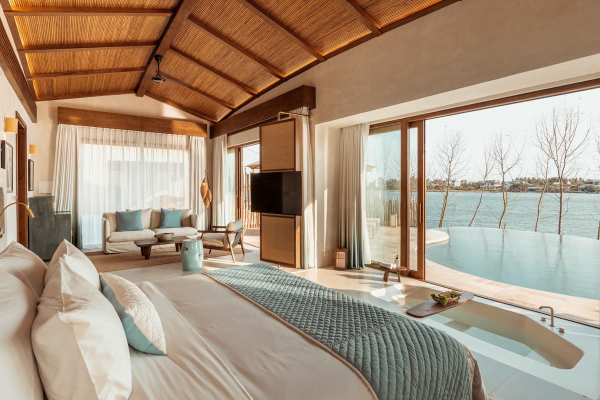 Un dormitorio con una cama grande, un sofá, un televisor y vistas a una piscina.