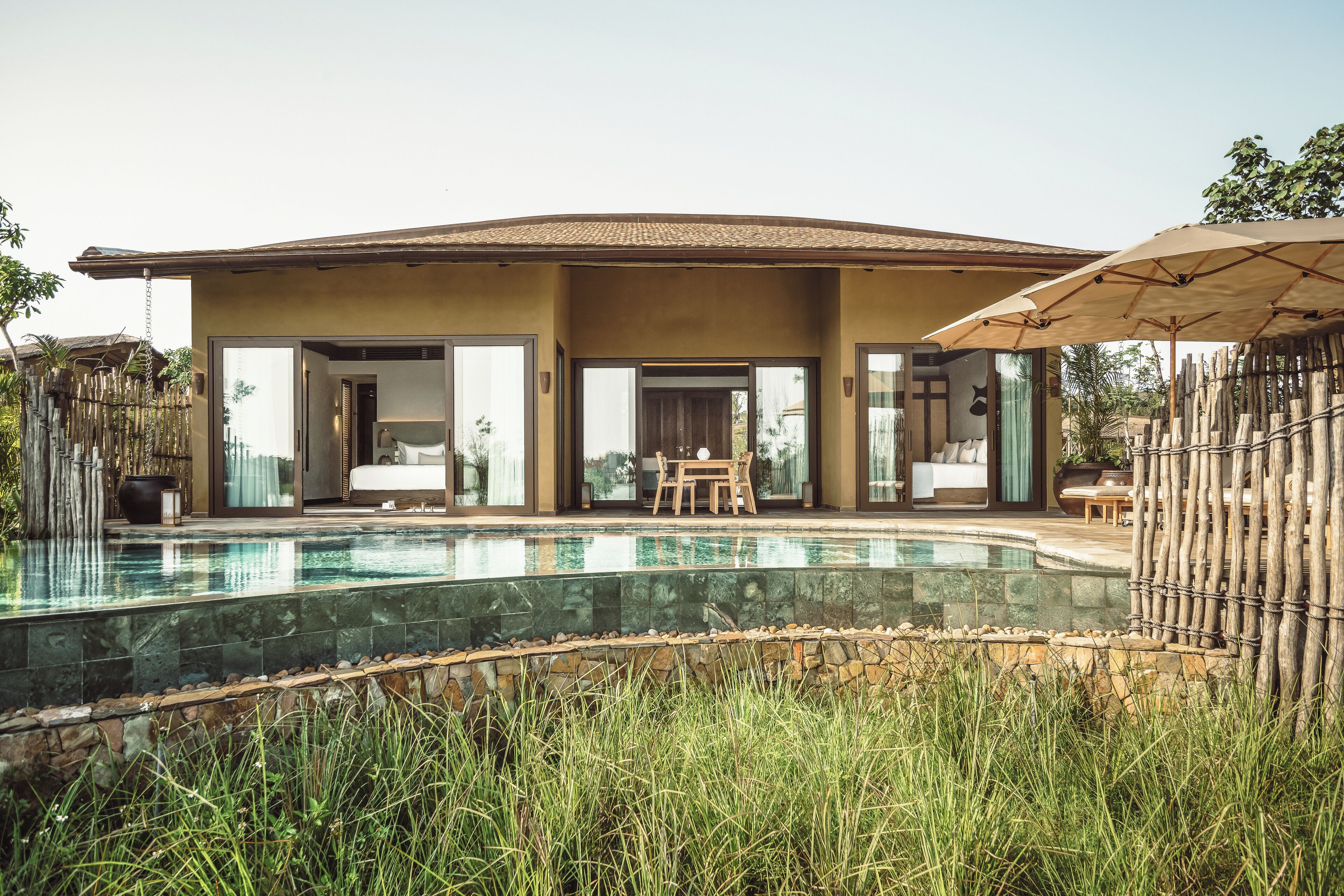 Uma casa moderna com piscina, varanda coberta e cerca de bambu.