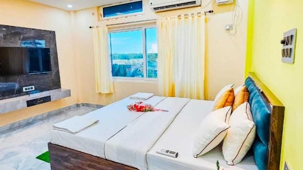 Een moderne slaapkamer met een bed, een televisie, een airconditioner en een raam met gordijnen.