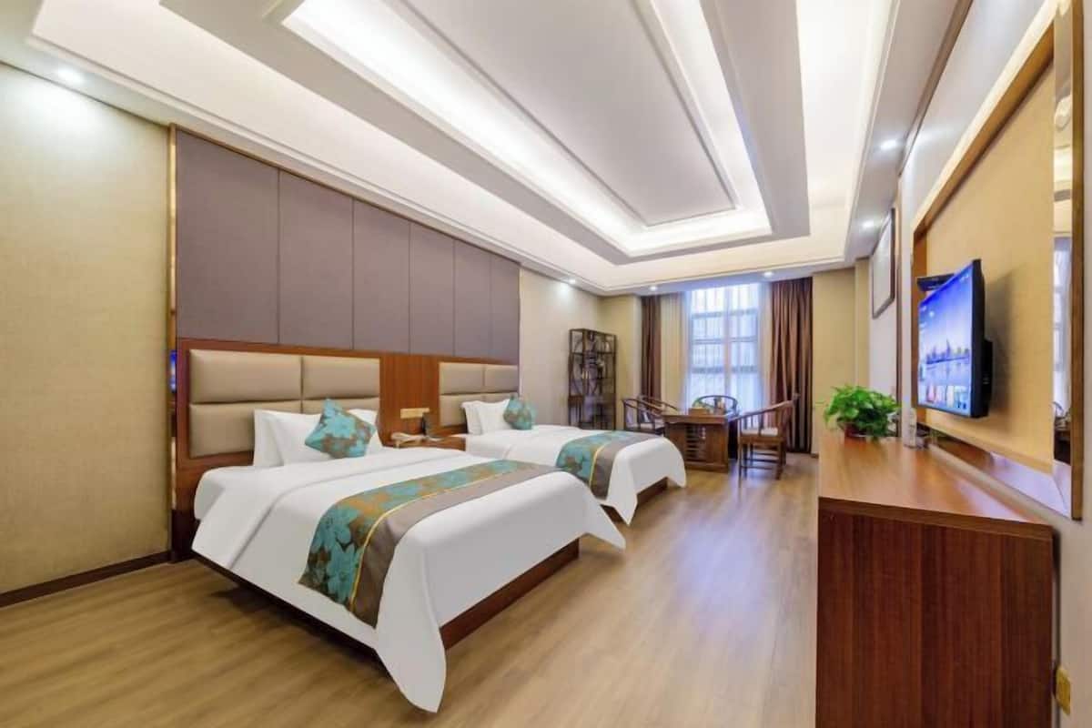 Habitación de hotel con dos camas, un escritorio, un televisor y una escalera.