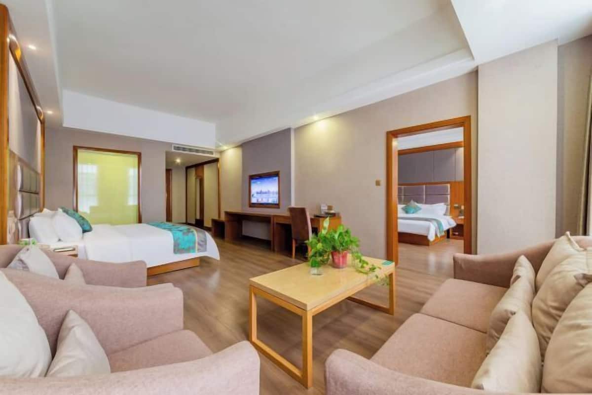 Una habitación de hotel con una cama, un sofá, una mesita y un televisor.