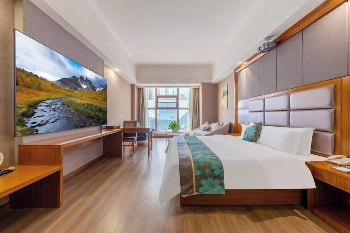 Una habitación de hotel con cama, escritorio, silla y un amplio ventanal.
