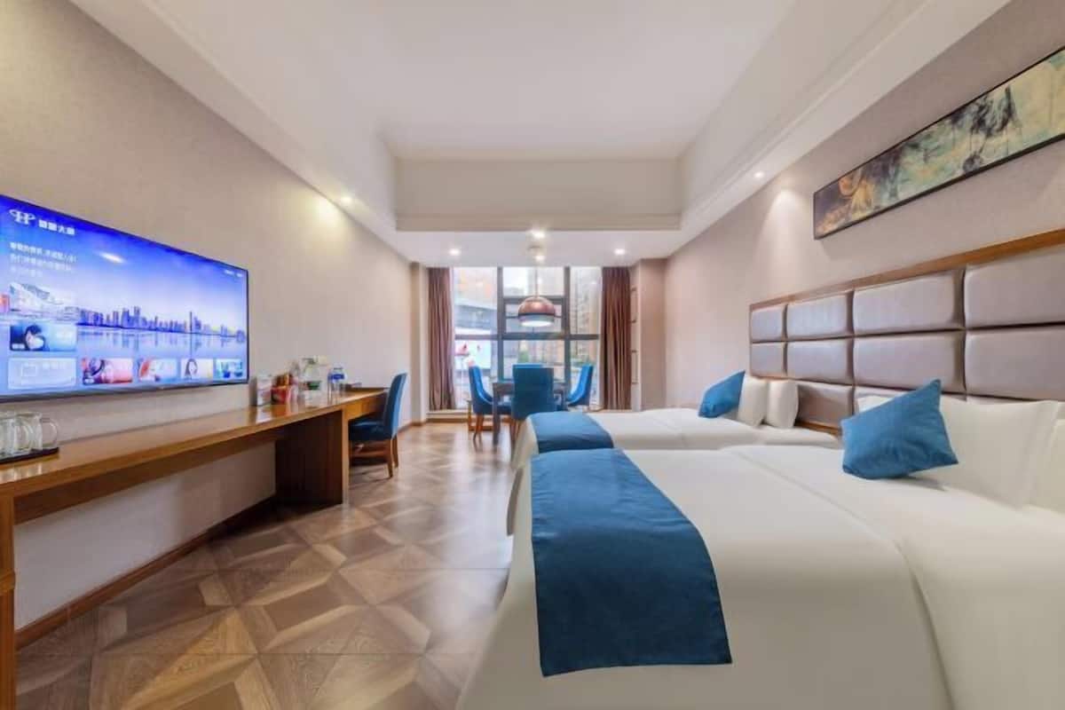 Una habitación de hotel con cama, escritorio, televisión y ventana.