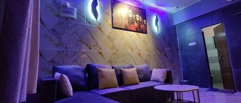 A modern lounge area with a sofa, a small round table, and a ceiling fan.