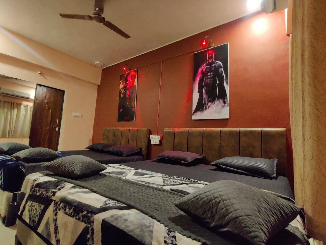 A hotel room with a large bed, multiple pillows, a ceiling fan, and two posters on the wall.