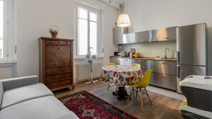 A compact kitchen with modern appliances, a dining area with a table and chairs, and a cozy seating area with a sofa. - GuestHost - Modern Apartment 150m from Turro M1 (Milano)