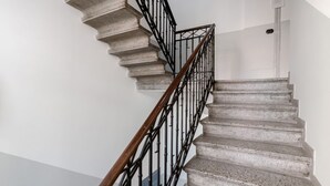 A spiral staircase with a wooden handrail and metal balusters, leading to a door. - GuestHost - Modern Apartment 150m from Turro M1 (Milano)