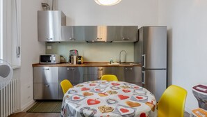 A compact kitchen with stainless steel appliances, a microwave, and a table with a heart-patterned tablecloth. - GuestHost - Modern Apartment 150m from Turro M1 (Milano)