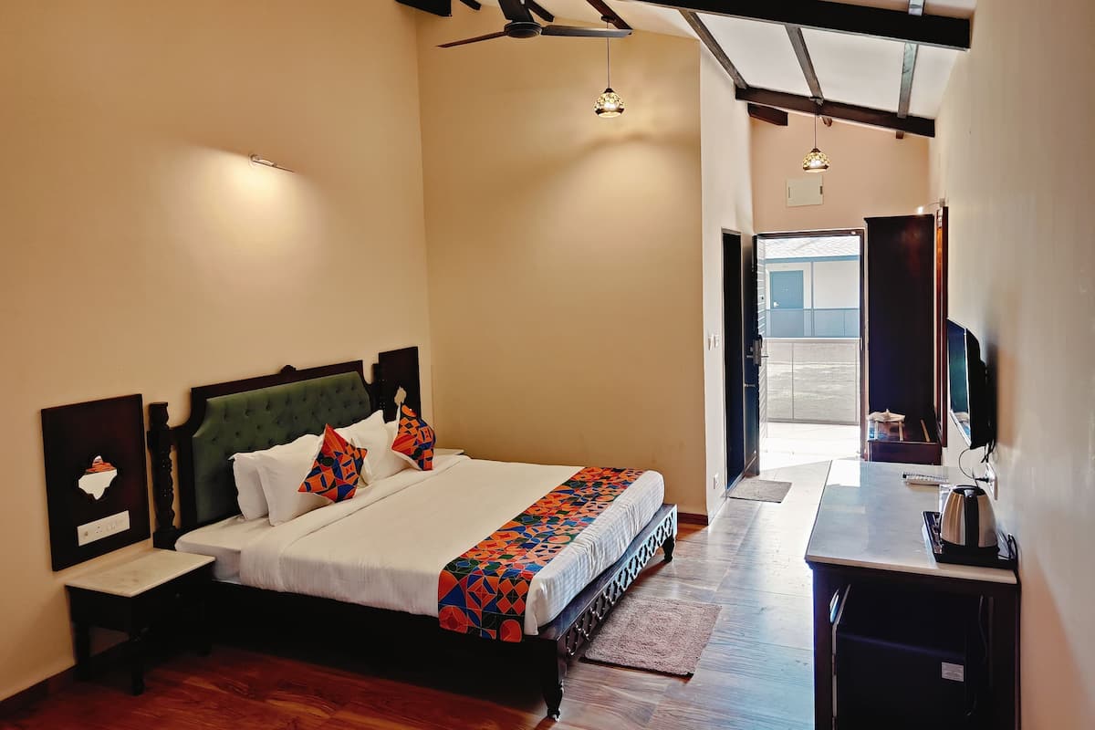 A bedroom with a bed, bedside table, and a desk with a kettle.