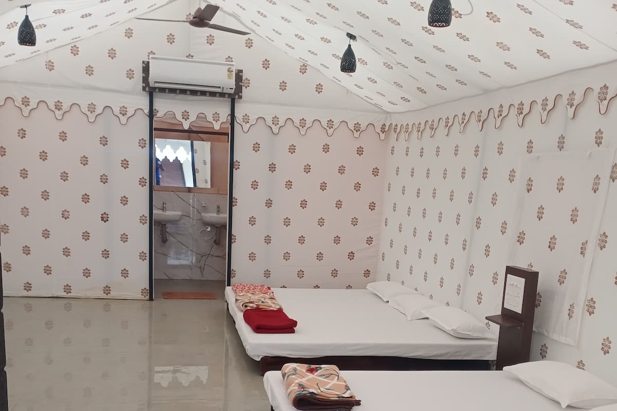 A room with two beds, a ceiling fan, and patterned walls.