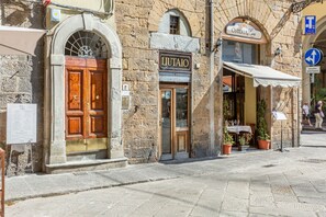 Een stenen gebouw met een houten deur waarop 'LIUTAO' staat en een bord met 'OSTERIA'.