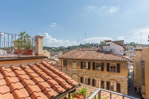A terracotta-tiled rooftop with a balcony, a stone building with arched windows, and a clear sky. - GuestHost - Charming 80 sqm apartment, for up to 8 people, located on the 4th floor of a building without a lift (40 steep steps at the entrance + 4 floors of stairs, not suitable for people with walking difficulties). The property is located in the hear (Firenze)
