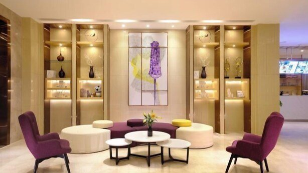 A modern lobby with purple chairs, a central round table, and shelves with decorative items. - Lavande Hotel (Guangzhou Convention and Exhibition Center, Nanzhou Metro Station) (Guangzhou)