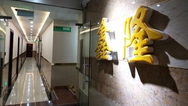 Un couloir d’hôtel avec une porte en verre, un sol en marbre et un panneau indiquant la direction du hall d’entrée.