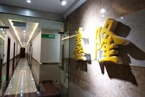Un corridoio d'hotel con una porta in vetro, un pavimento in marmo e una segnaletica che indica la direzione verso la hall.