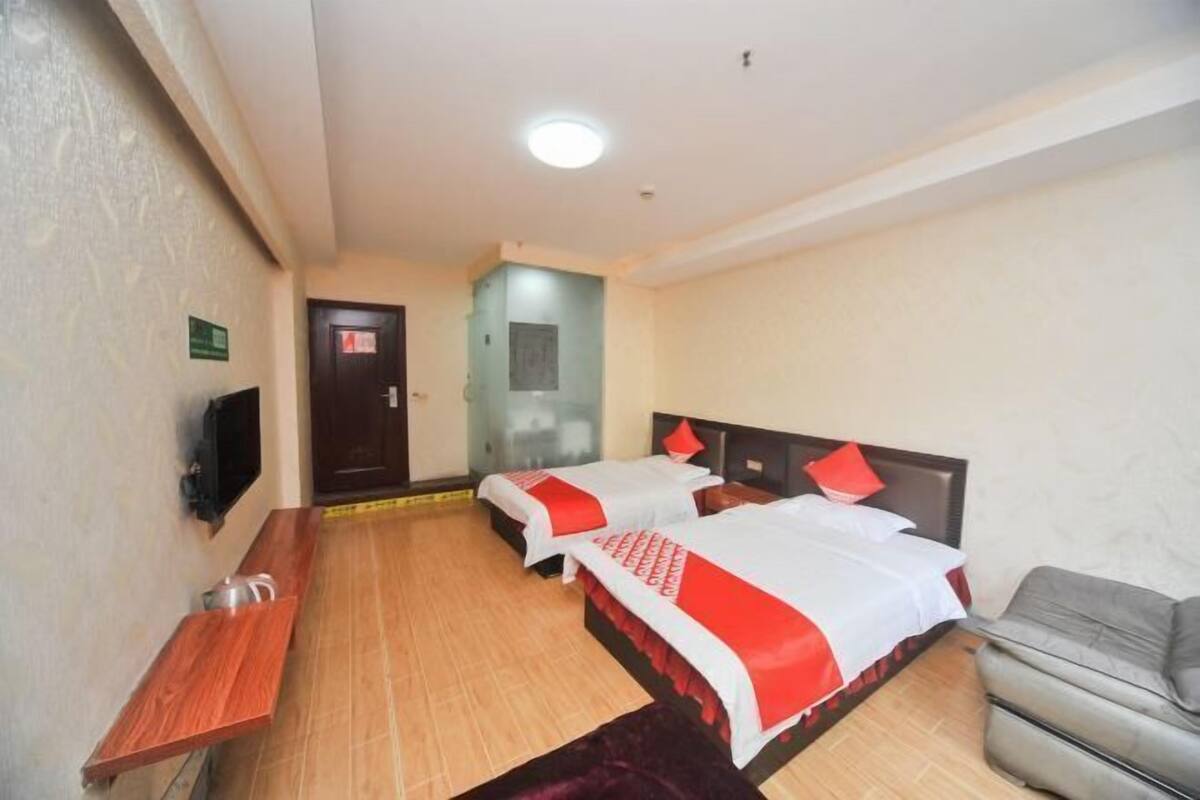 Une chambre d’hôtel avec deux lits, une télévision, un petit bureau et un canapé.