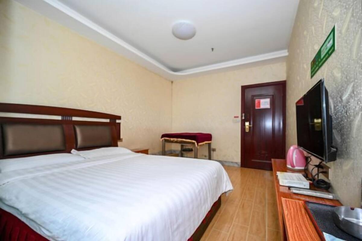 Une chambre d’hôtel avec un lit, un bureau, une chaise, une télévision et une porte.