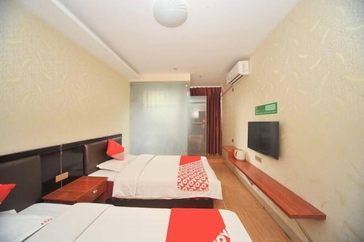 Une chambre d’hôtel avec deux lits, une télévision, une petite table et un banc.