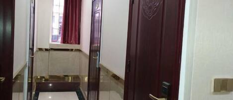 A hotel hallway with a marble floor, a red curtain, and a door with a number plate.