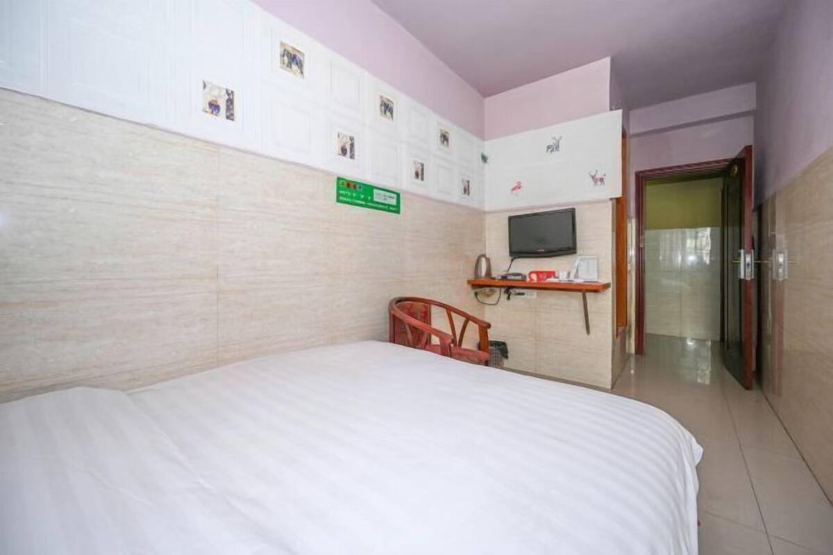 Une chambre d’hôtel comprenant un lit, un petit bureau avec une chaise, une télévision et une porte donnant sur une autre pièce.