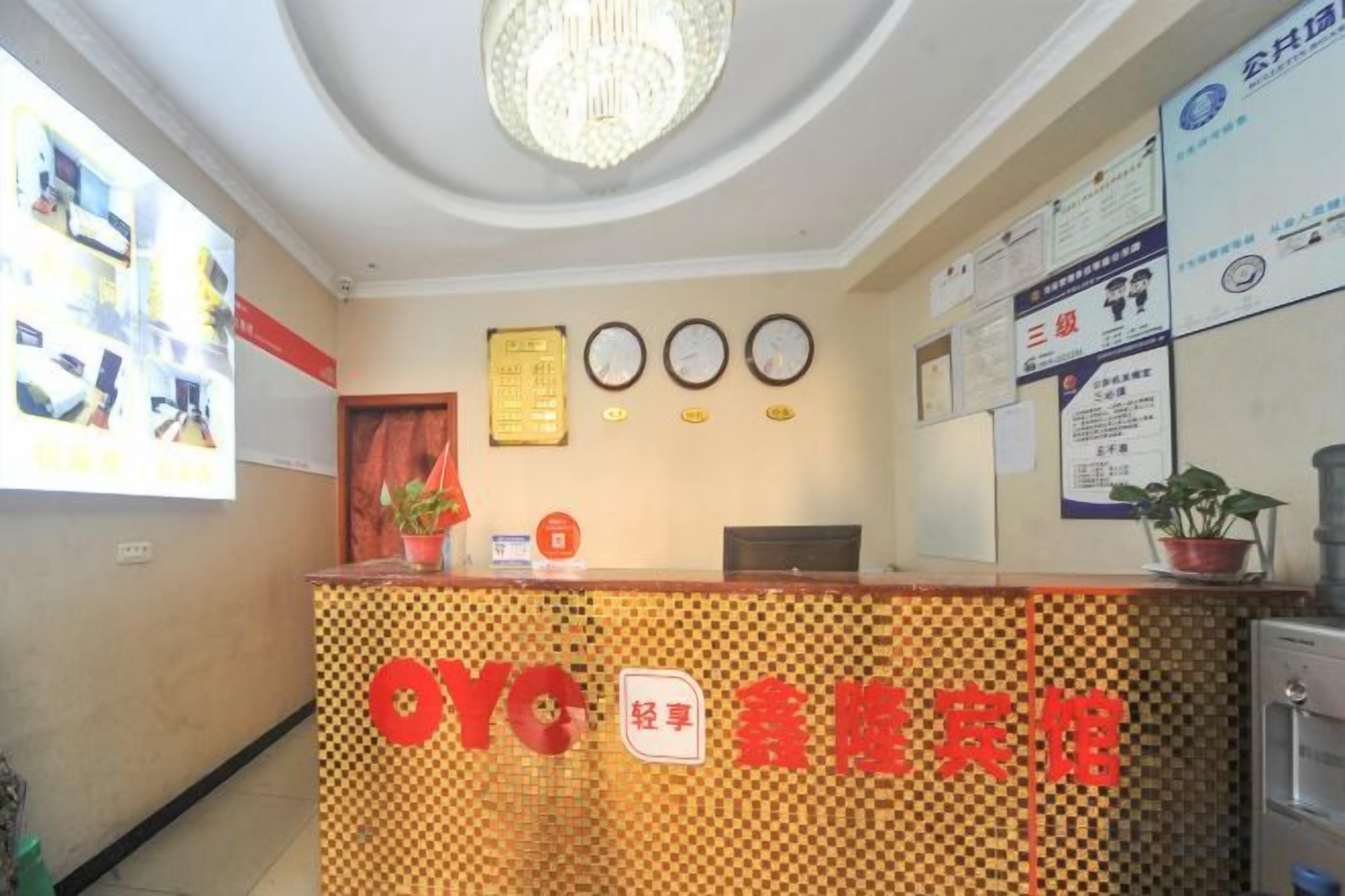 A reception desk with a checkered pattern, a chandelier, and several clocks on the wall.