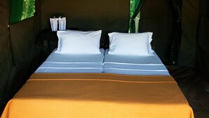 A tent with a bed featuring two pillows and a striped blanket. - Belihuloya Adventure Camp (Rathnapura)