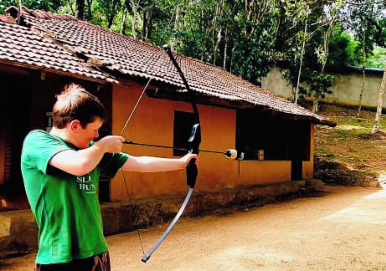 Una persona con una camisa verde apuntando un arco a una diana.