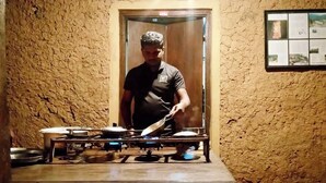 A person cooking in a kitchen with a stove and pots. - Belihuloya Adventure Camp (Rathnapura)