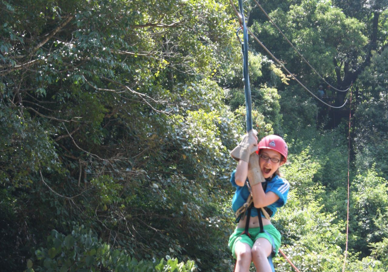 A person on a zip line in a forested area.