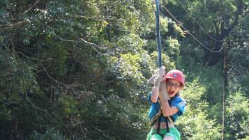 A person on a zip line in a forested area.
