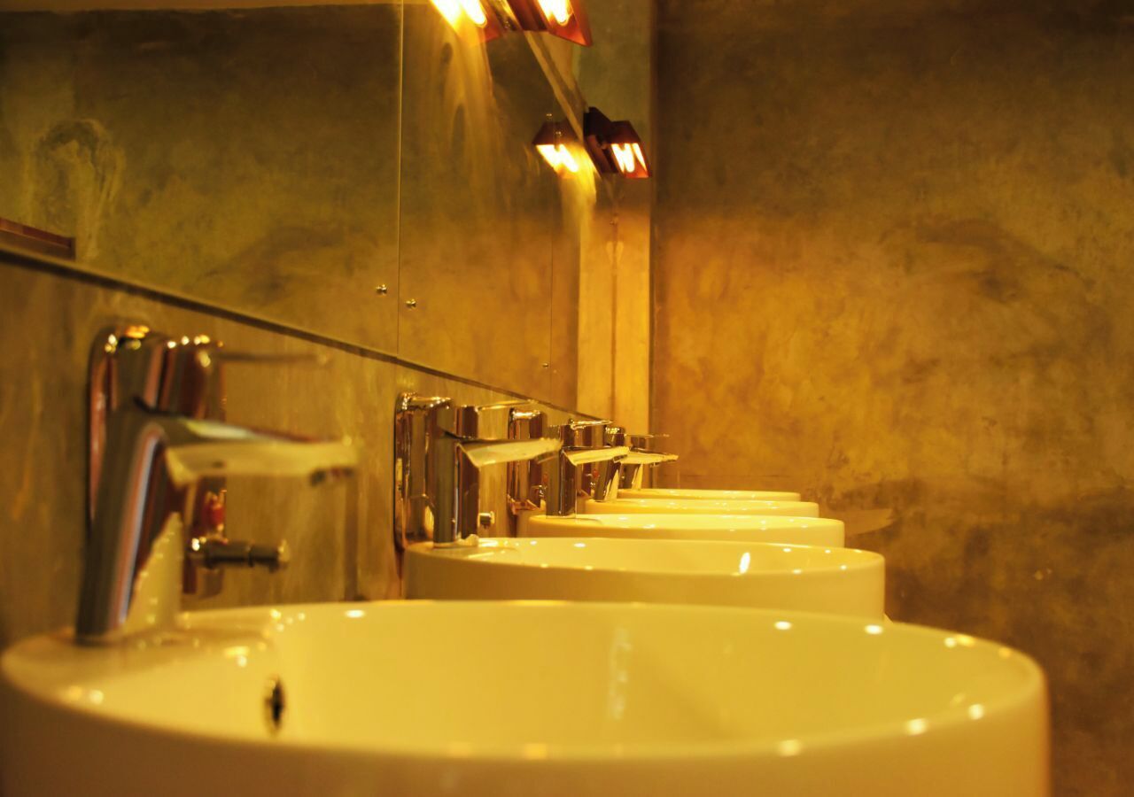 Une rangée d’éviers avec des miroirs et des robinetteries chromées dans une salle de bain.