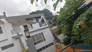 A modern multi-story residential building with balconies, a gated entrance, and surrounding greenery. - Transit Stay (Bengaluru)