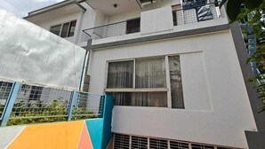 A two-story building with a balcony on the upper floor, a garage door, and a clear sky in the background. - Transit Stay (Bengaluru)