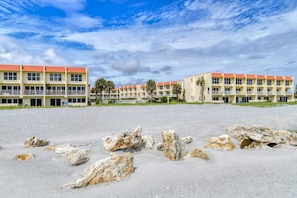 A beachfront hotel with multiple floors, outdoor seating, and palm trees.