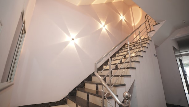 A modern staircase with a glass railing and a geometric ceiling design. - Hotel Inspira Residency- Near Bombay Hospital (Indore)