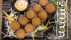 A black plate with croquettes, shredded vegetables, and a small bowl of sauce. - Hotel Inspira Residency- Near Bombay Hospital (Indore)