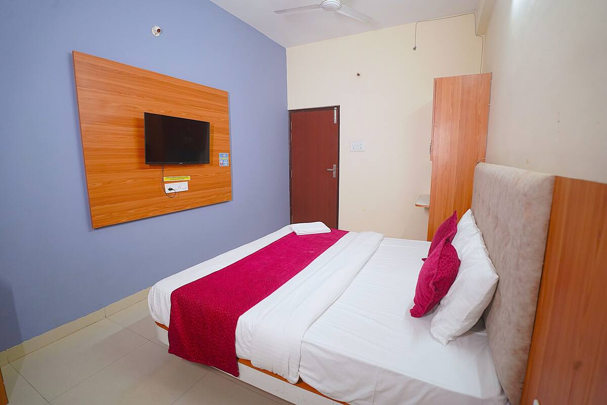 A hotel room with a bed, a television mounted on the wall, and a door.