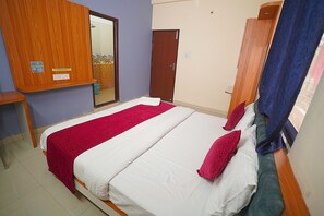 Habitación de hotel con cama, armario de madera, espejo y puerta.