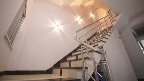 A modern staircase with a metal railing, leading to a landing with a light fixture. - Hotel Inspira Residency- Near Bombay Hospital (Indore)