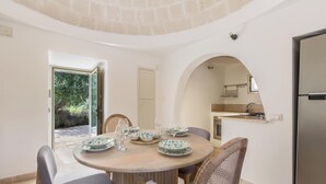 A dining area with a round table, chairs, and a view of the kitchen through an archway.