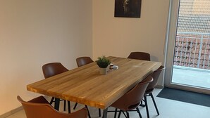 Sala de conferências com mesa de madeira, seis cadeiras marrons, uma pequena planta em vaso e uma obra de arte emoldurada na parede.