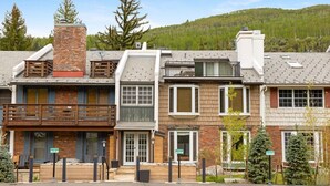 A row of townhouses with a shared driveway, wooden balconies, and a mountain backdrop.