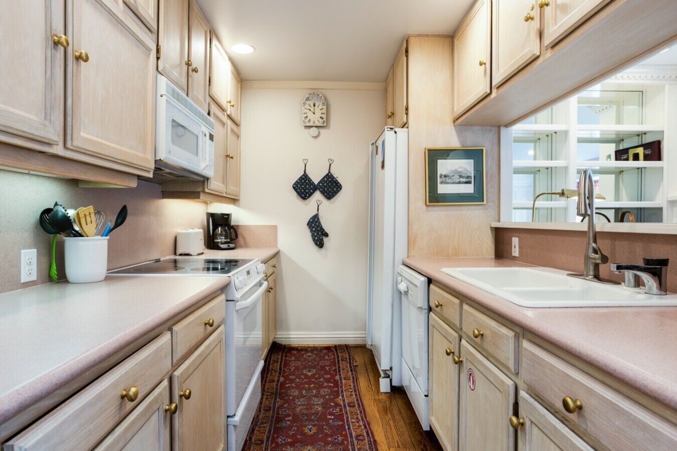 A compact kitchen with wooden cabinets, a microwave, a coffee maker, and a refrigerator.