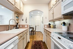 A kitchen with a sink, stove, cabinets, and a dining area with chairs and a table. - Central Vail Condo - Short Walk to Ski & Village (Vail)