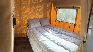A single bed with a white duvet in a room with wooden walls and a window.