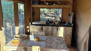 A compact kitchen with a wooden table, a small island, and a window overlooking a forest.