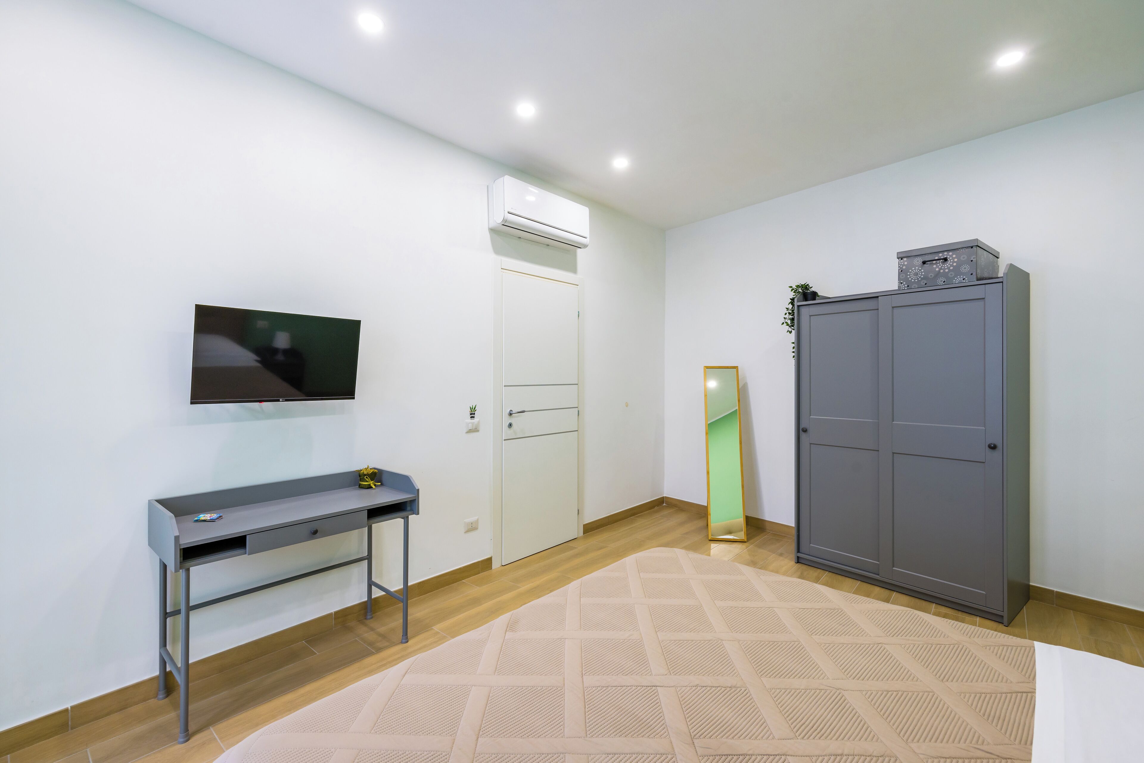 Une chambre comprenant un lit, un bureau, une armoire, un téléviseur et un appareil de climatisation.